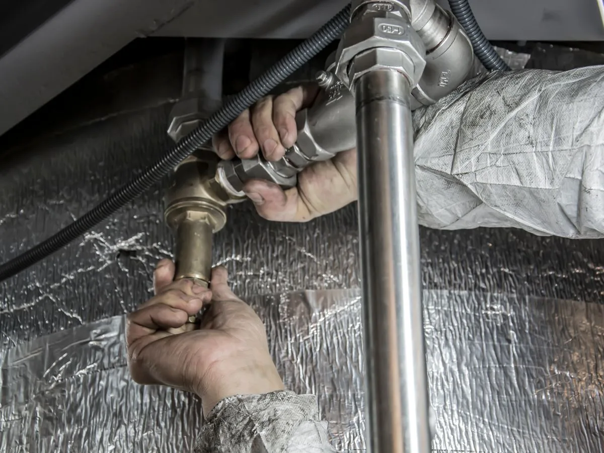 Technician installing steel pipe fittings during a septic system repair