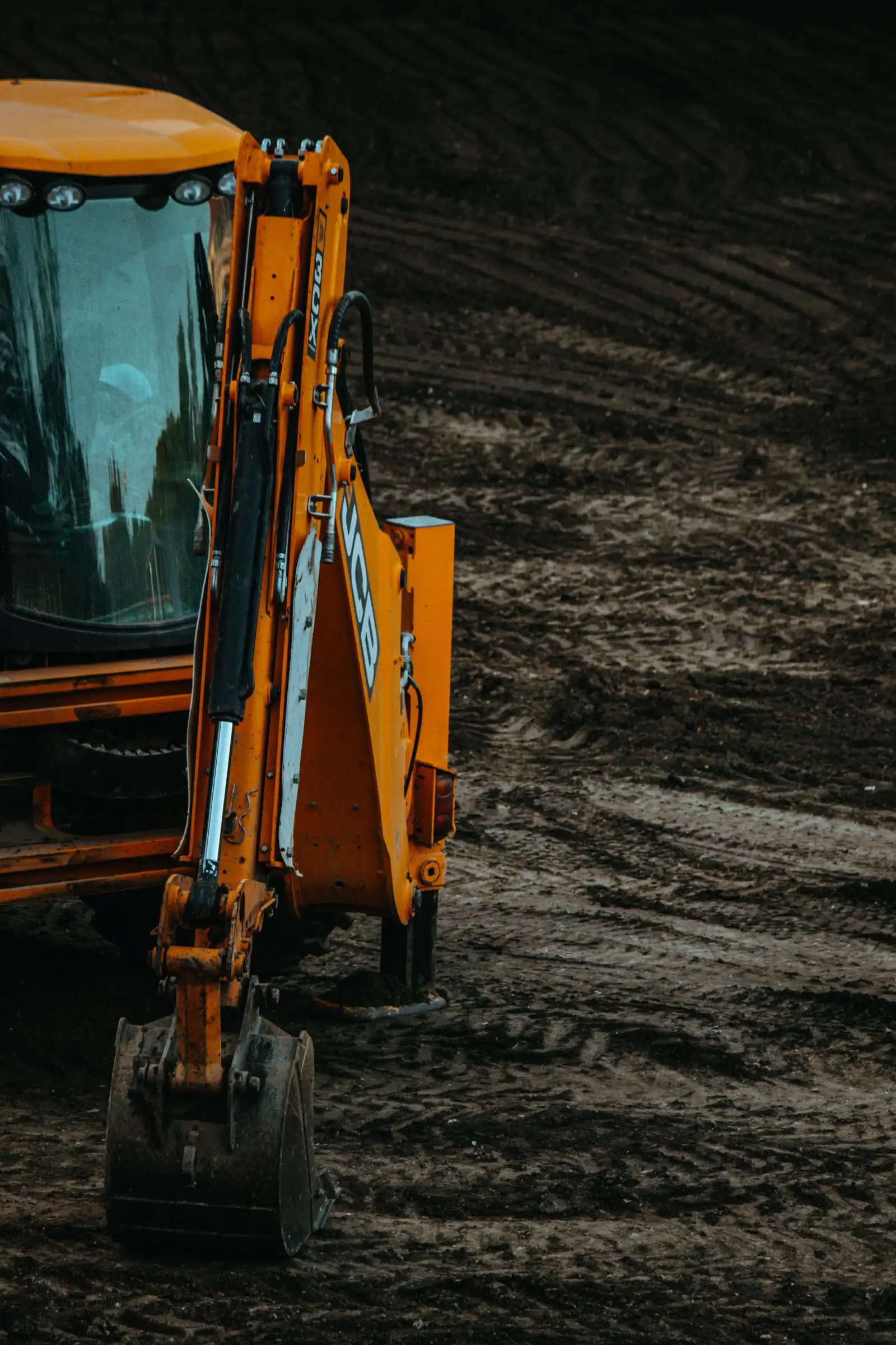 An excavator parked at a dirt construction site prepared for septic system excavation