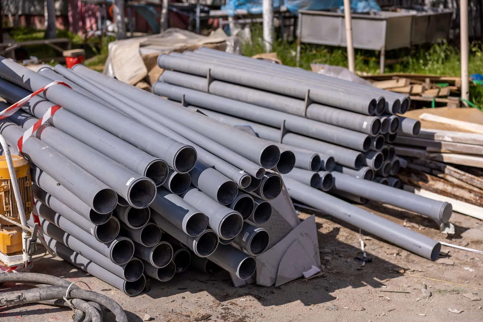 Stacks of gray PVC pipes staged at a septic system installation site