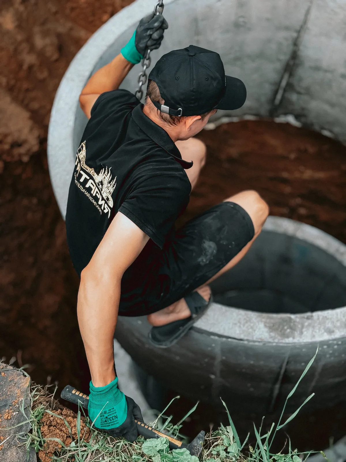 A technician setting a concrete tank riser into the ground during septic system installation