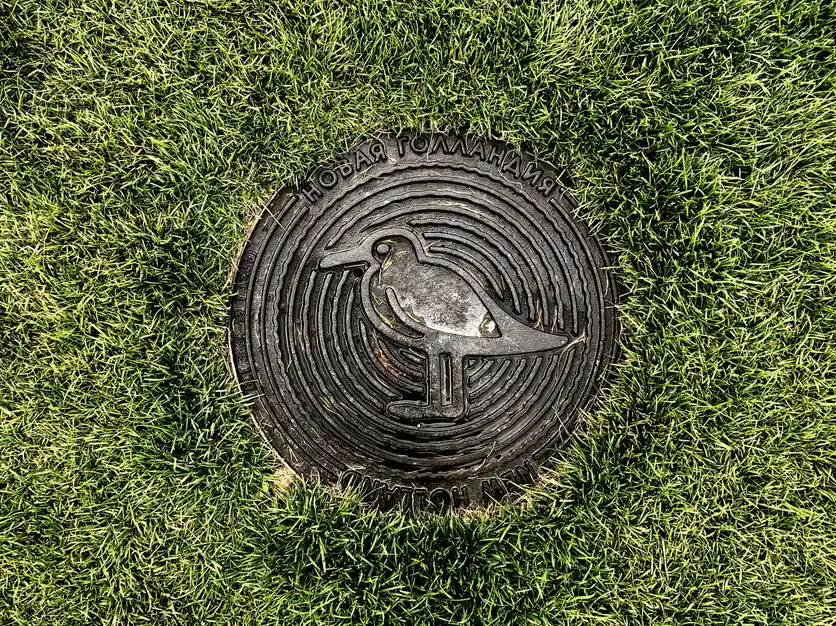 A round metal access cover set flush into a grass lawn