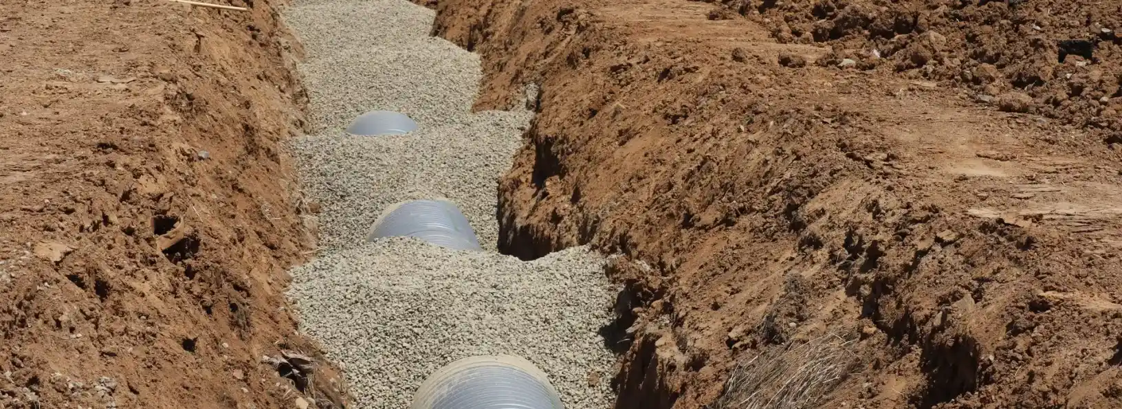 Drainage pipe being laid in a gravel-lined trench during a septic system installation